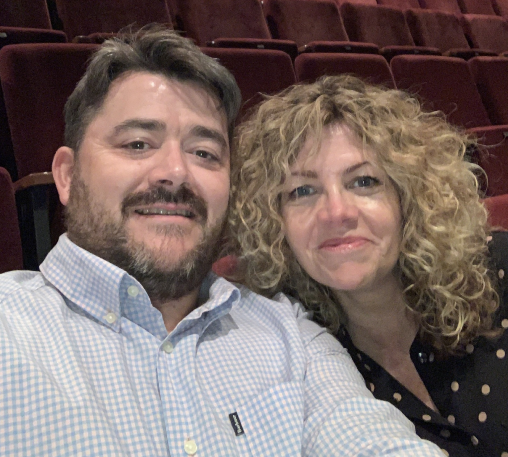 Inspector Darren Jones and his wife Nicola smile at the camera seated in a cinema
